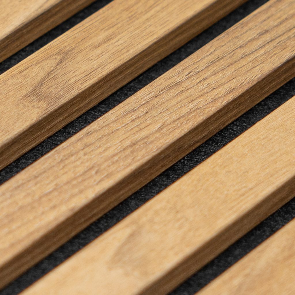 Nahaufnahme eines WoodUpp Akustikpaneels: helle, schmale Holzlamellen mit sichtbarer Maserung und feiner Oberflächenstruktur, gleichmäßig parallel angeordnet und leicht abgeschrägten Kanten, auf einem dunklen, schallabsorbierenden Filzträger montiert. Diese WoodUpp-Lamellen vereinen dekoratives Design mit warmem Holzton, langlebiger Lackierung und hochwertiger Verarbeitung.