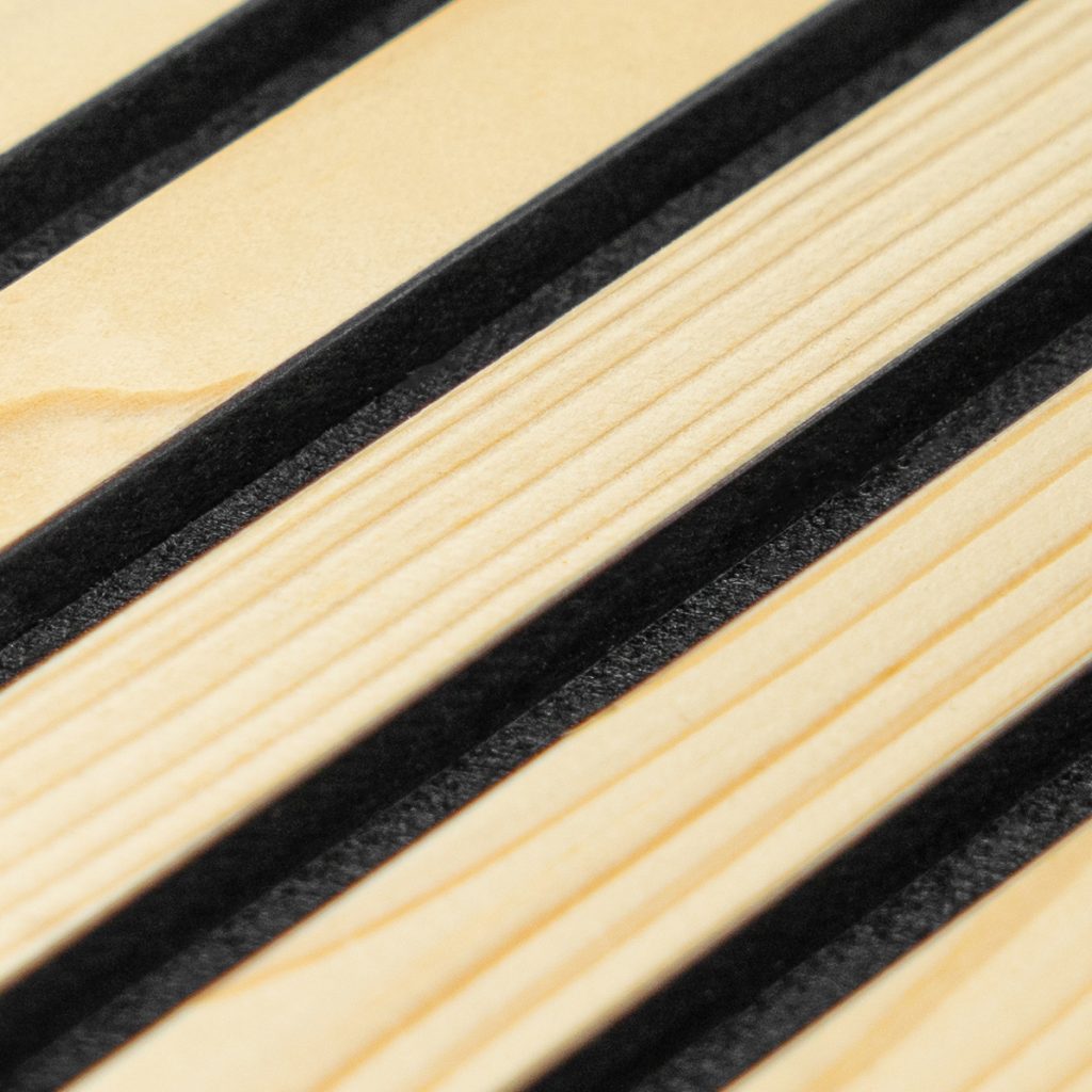 Nahaufnahme eines WoodUpp Lamellenpaneels: diagonale, helle Holzlamellen mit feiner Maserung, präzise gefräst und in gleichmäßigen Abständen angeordnet, getrennt durch schmale schwarze Filz- oder Gummistreifen. Das Bild zeigt Oberfläche, Fugenstruktur und Detailqualität eines WoodUpp Lamellen- beziehungsweise Akustikpaneels mit warmem, natürlichem Farbton, ideal für moderne Wandverkleidung.